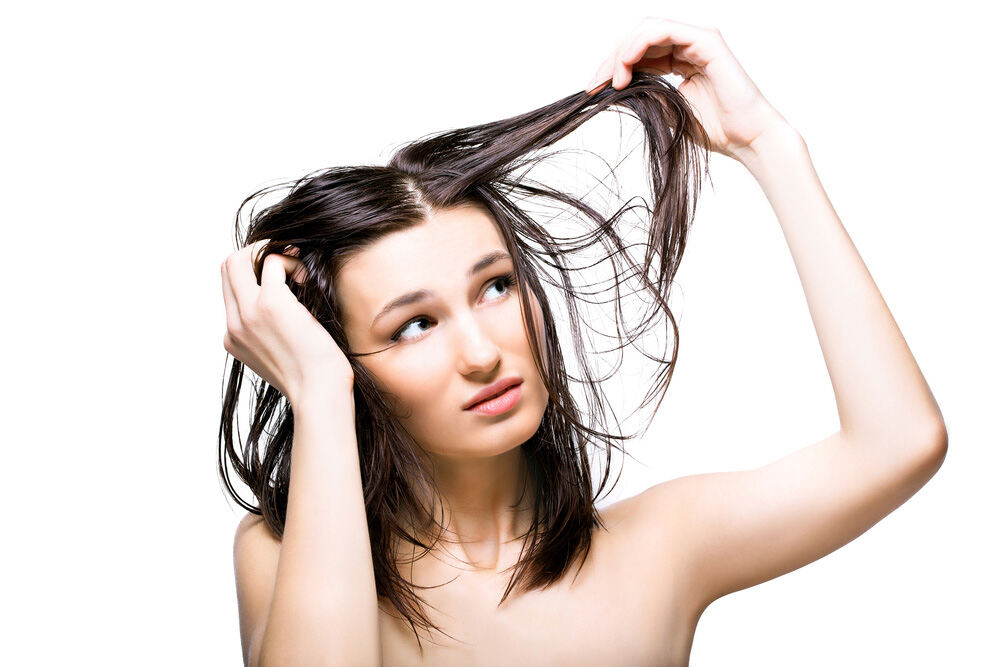 brunette woman looking at her hair strands